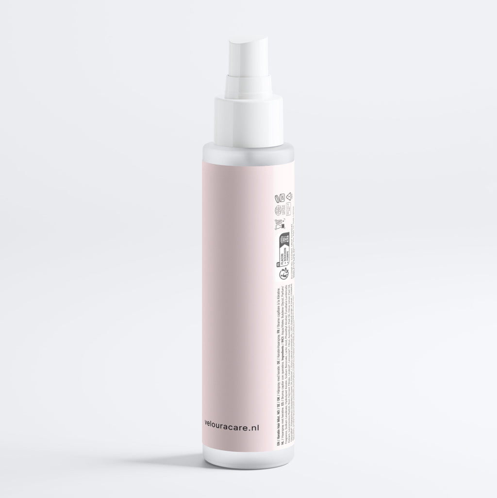 Flesje met roze etiket en witte spraydop van de Keratin Shine Leave-In Hair Mist voor glanzende en verzorgde haarverzorging.