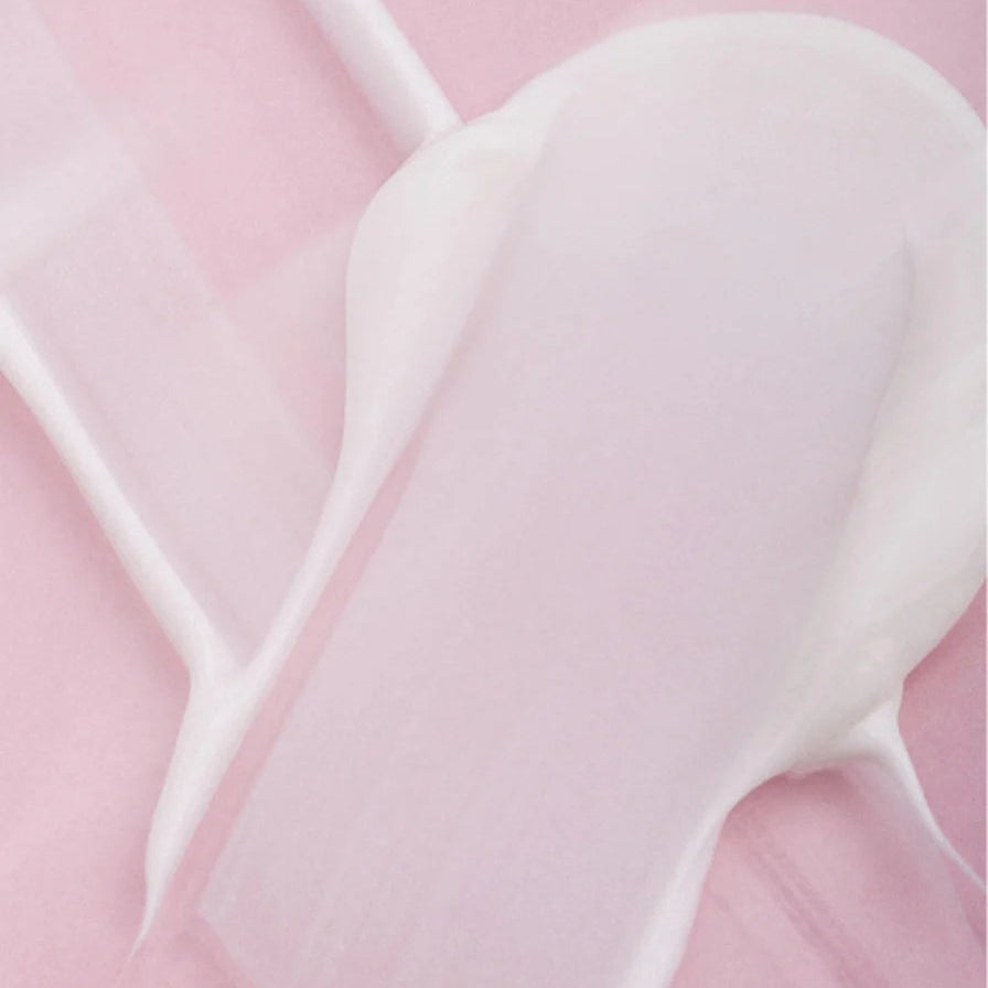 Romige textuur van Anti-Age Oogcrème op een zachte roze achtergrond, die natuurlijke huidverzorging en verzorgende eigenschappen benadrukt.